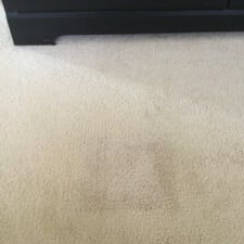 A white carpet with brown stains on it.