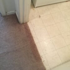 A dirty floor and tile in the corner of a room.