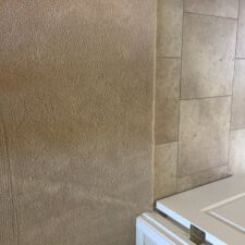 A bathroom with beige tile and white walls.